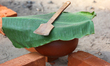 Clay pot covered with a banana leaf containing pongala seen as Hindu women finish the fina...