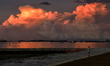 A man watches the sunrise as vessels are seen anchored along the southern coast on June 15...