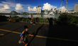 People jog and cycle along the bayfront with the city skyline seen in the background at Ga...