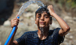 A Palestinian boy pours water over his head near his home in a poor area of the Gaza city...