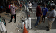 People wearing protective face mask w2ait in line to refill their oxygen bottles at a refi...
