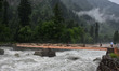 People walk on a footbridge during heavy rainfall in Sonmarg tourist spot, Indian Administ...