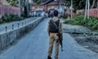 A Jammu and Kashmir Police Cop (JKP) stops public movement after security forces launched...