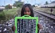 A slum child holds her slate board where she writes basic numbers as her lesson during a p...