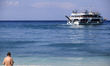 A tourist enjoy a summer evening at Xigia beach as a boat with other tourists leaves in Za...