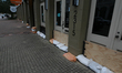 Shop owners line their doors and windows with sand bags and wooden boards to keep flood wa...