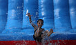 A Palestinian boy is splashed with water as he plays on a slide during summer activities o...