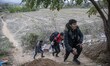 Group of three young asylum seekers walking up to a hill as they return from their attempt...