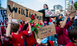 A group of people wearing red clothes and placards in memory of Rosa, a girl who died duri...