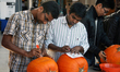 Contestants compete in a pumpkin carving competition the day before Halloween in Ontario,...
