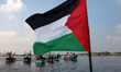 Palestinians riding boats hold Palestinian flags during a protest against the killing of 1...
