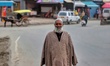 An Elderly kashmiri man smiles as he wear a Pheran ( a long woolen outfit) on a cold day i...
