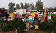 A woman takes a nap near her stall as people buy garlands to decorate their homes at a who...