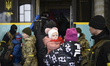 A woman holds a child before boarding an evacuation train to Poland at the Lviv railway st...