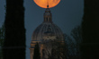 The Full Pink moon sets behind Santa Maria degli Angeli Basilica church in Assisi, Umbria,...