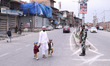 People walk as Indian forces stand outside Kashmir's grand mosque Jamia Masjid on Eid ul F...