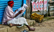 Elderly man reading a newspaper along the roadside in the Poombarai Village in Kodaikanal,...
