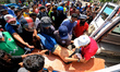 An injured Sri Lankan anti-government protester is carried in to an ambulance by fellow pr...