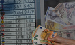 A person holds banknotes of the Euro in front of a board showing the selling and buying ra...