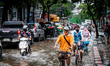 Bicyclists pedal through heavy traffic on a flooded street in Bangkok on July 21, 2022. 