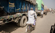 A man drives past hundreds of trucks on his bicylce on the road that leads to the closed b...