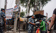 Nepalese police officers check the belongings of a pedestrian at the border crossing betwe...