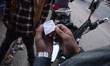 A motorcyclist presents his token that allows him to collect his allocated amount of fuel...