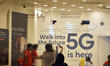 A girl takes a selfie picture inside an Airtel store where 5G logo is written on a door of...