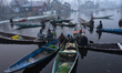 Vendors sell vegetables at the floating vegetable market on a cold foggy winter morning in...