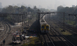 A suburban train is seen with a background of highrise buildings which are partially visib...