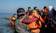 A man holds her child on a beach near to the town of Mytilene after crossing a part of the...