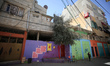 A Palestinian walks past the facades of houses painted by artists in Gaza City, on March 1...