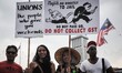 Protesters hold placards during a protest against the goods and services tax (GST) in conj...