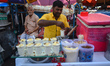 A person is making lassi (milk-based cold drinks) on a street side food stall on a hot sum...