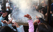 Visitors throw themselves smoke at the Sensoji temple in Asakusa on January 6, 2016, Tokyo...