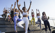 Participants in Sunrise Wine Yoga class perform a yoga exercise with a wine glass, in Bang...