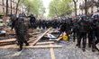 Riot police from the Gendarmerie Mobile straddle a barricade made with construction equipm...