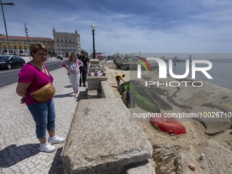 Several people are seen looking at sculptures on the riverbank near a beach on the Tejo river, in the Baixa neighborhood, Lisbon. 02 May 202...