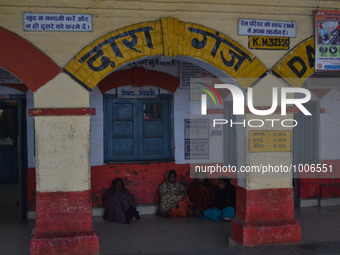 Indian passengers gather under a blanket as they wait for a train at Daraganj railway station in Allahabad on January 18,2016. Dense winter...