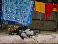 An indian begger sleeps on a footpath of a busy street during a cold and foggy day in Allahabad on January 18,2016. A cold wave over norther...
