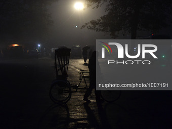 An indian rickshaw puller waits foor passengers at district bus statioon  during a cold and rainy morning in Allahabad on January 19,2016.A...