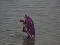 An indian woman prays as she takes a holy dip in Yamuna River during a cold and rainy day in Allahabad on January 19,2016.A cold wave over n...
