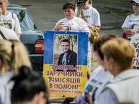 Mother of her captived son holds a banner with his portrait in a concentration of relatives of deported civilians of the ukrainian village D...
