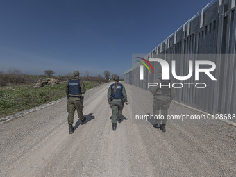 Border police walking alongside the fence. Greek border police officers patrol along the steel fence next to Evros river between Greece and...