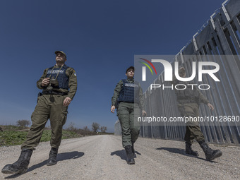 Border police walking alongside the fence. Greek border police officers patrol along the steel fence next to Evros river between Greece and...