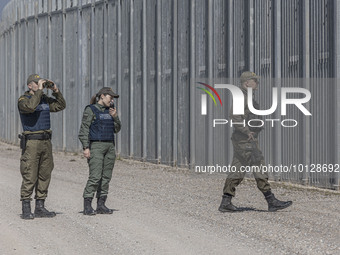 Police officer searches the area with binoculars while another officer it talking to the radio. Greek border police officers patrol along th...