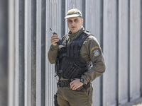 Police officer searches the area and talks to the radio. Greek border police officers patrol along the steel fence next to Evros river betwe...