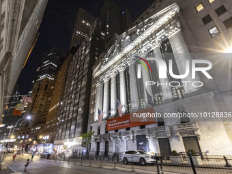 Night view of the illuminated exterior of New York Stock Exchange with American flags. NYSE building has the style of classical architecture...