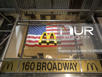 An illuminated lofo of McDonald's corporation in front of an American flag in the storefront at Broadway avenue in New York City, USA. McDon...