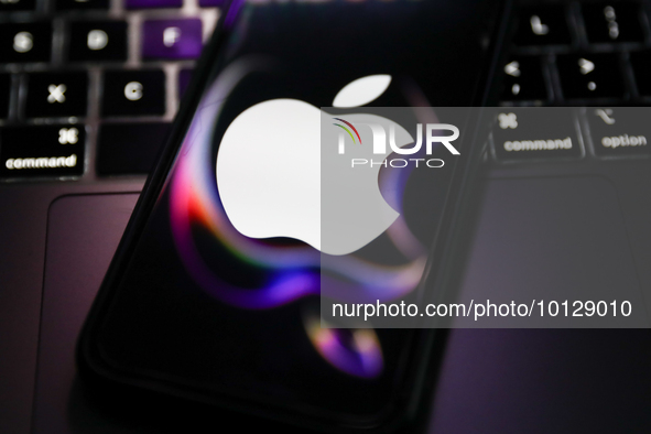 A laptop keyboard and Apple logo displayed on a phone screen with Apple website reflected on it are seen in this illustration photo taken in...